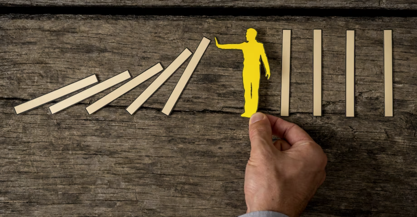 A hand places a yellow paper figure between falling dominoes, illustrating strategies to protect profit margins from MRO
